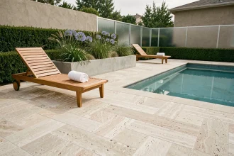Aménagement de bord de piscine moderne avec dalles en travertin, transats en teck et jardinières en béton plantées d'agapanthes